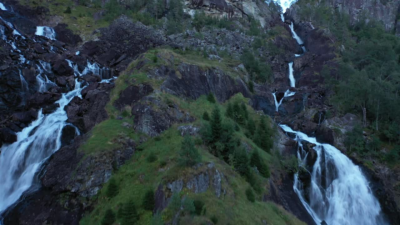 Approaching Låtefoss Norway - close aerial passing branch of tree and moving upwards close to waterfall during dusk hours - Quiet moody evening aerial