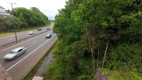 timelapse of very fast cars passing camera on m4 motorway with trees on roadside with hard shoulder lane and motion blurred vehicles heading to their destination