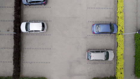 Visto-Desde-Arriba,-Un-Estacionamiento-Al-Aire-Libre-En-Un-Entorno-Urbano-Está-Lleno-De-Autos-Cuidadosamente-Dispuestos,-Capturados-En-Una-Toma-De-Dron-De-Barrido-A-Plataforma-Rodante