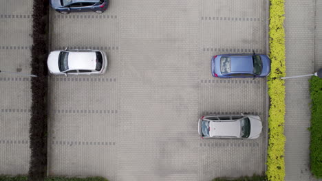 visto desde arriba, un estacionamiento al aire libre en un entorno urbano está lleno de coches cuidadosamente dispuestos, capturado en una toma de drone de barrido a dolly