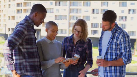 Young-mixed-race-business-team-discussing-over-digital-tablet-in-the-balcony-of-office-4k