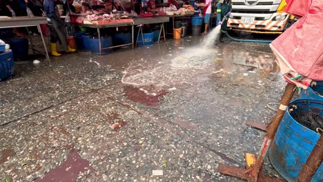 worker hosing down wet market floor