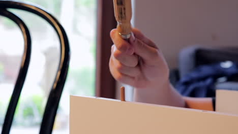 joven construyendo un estante, usa un destornillador como martillo incorrectamente