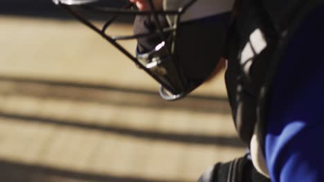 Jugadora-De-Béisbol-Caucásica-Sentada-En-Un-Banco-Con-El-Equipo,-Poniéndose-Casco-Y-Guante