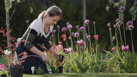 a woman plants flowers in the garden near her house