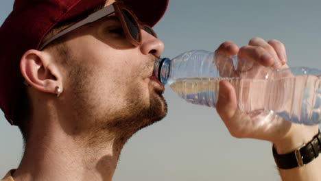 un homme assoiffé avec des lunettes de soleil et une bouteille d'eau