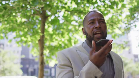 Happy-african-american-man-in-city-walking-and-using-smartphone