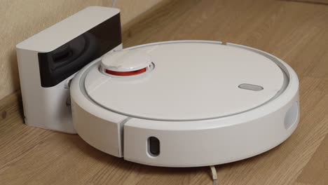 white robotic vacuum cleaner starts cleaning from its charging station