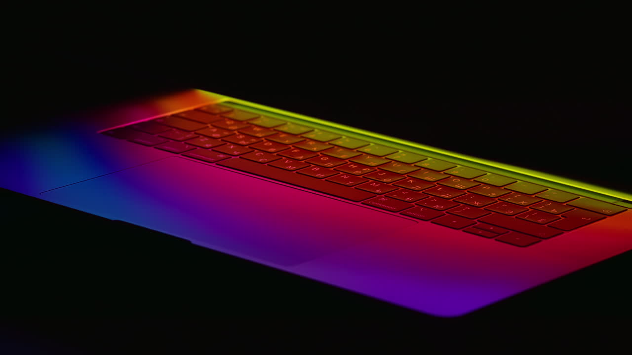 revelación giratoria de un teclado de portátil brillante de neón aislado en un fondo negro