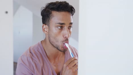 Biracial-man-brushing-teeth-in-bathroom-in-the-morning,-slow-motion