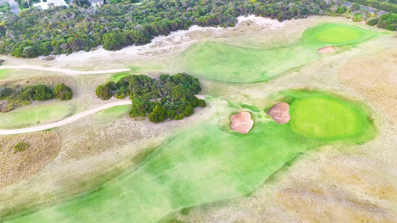 Drone footage captures lush golf course and scenic coastline in Barwon Heads, Victoria, under soft daylight