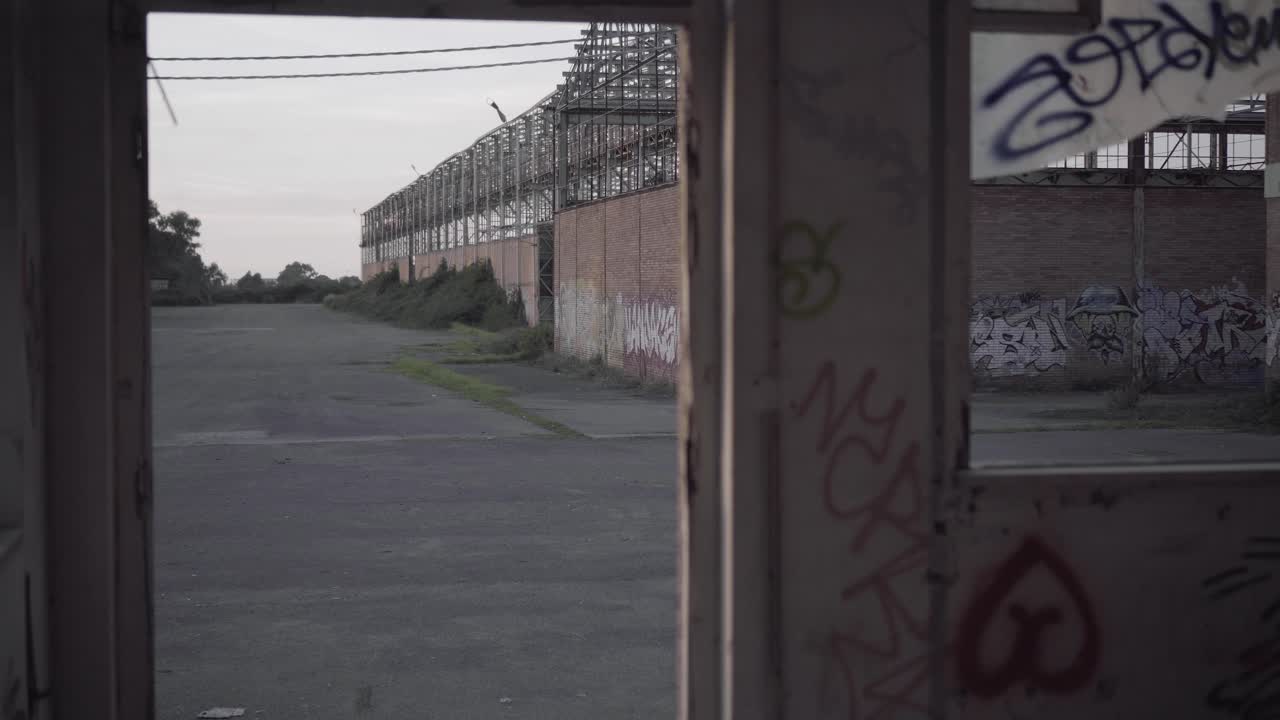 Abandoned warehouse - view from a broken window with murals at sunset