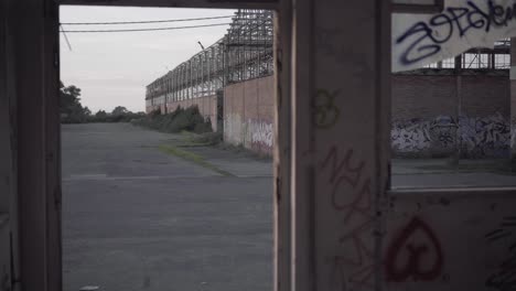 abandoned warehouse - view from a broken window with murals at sunset