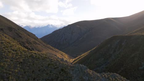 Low-drone-flight-over-rugged,-grassy-mountains-in-dramatic-conditions