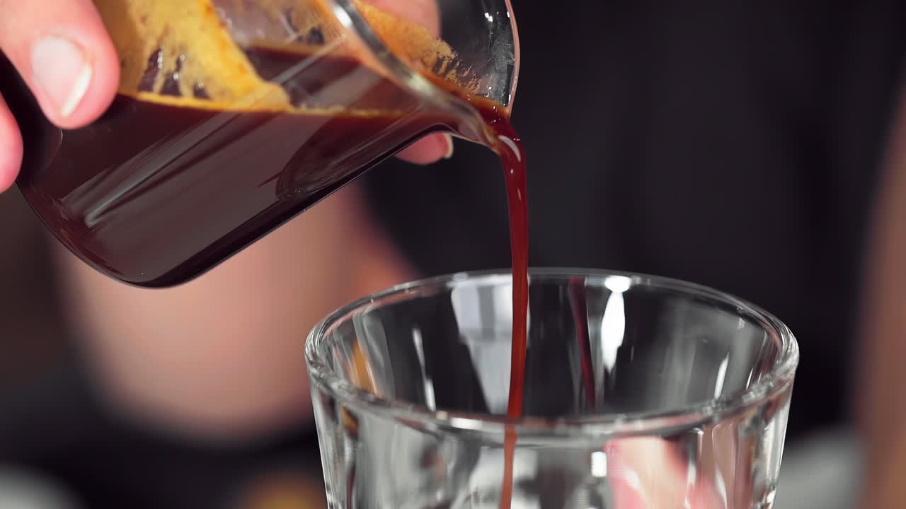 Mano del barista che versa il caffè in una tazza di vetro al rallentatore.