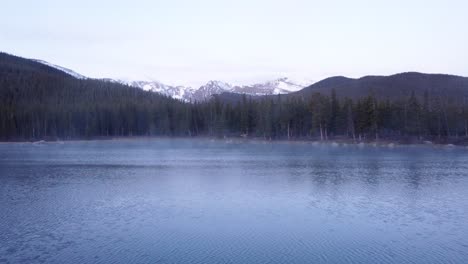 Vapor-Saliendo-Del-Lago-De-Montaña-De-Colorado-Con-Montañas-Rocosas-Cubiertas-De-Nieve-En-El-Fondo,-Panorámica-Izquierda-Aérea