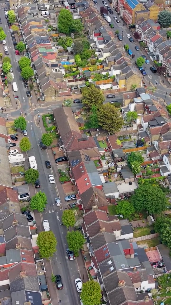 Case vittoriane a Leyton, Londra, riprese con drone, passando accanto ai Coronation Gardens sulla sinistra. Ripresa aerea di una soleggiata giornata estiva che mostra tetti residenziali, strade, auto parcheggiate e verde urbano. Verticale