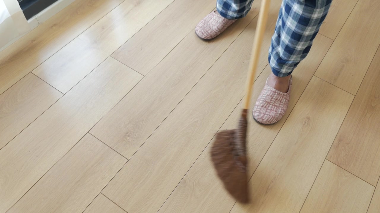 Person Sweeping Wooden Floor with Traditional Broom