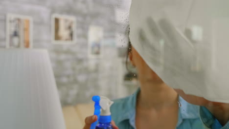 una mujer rociando una ventana.