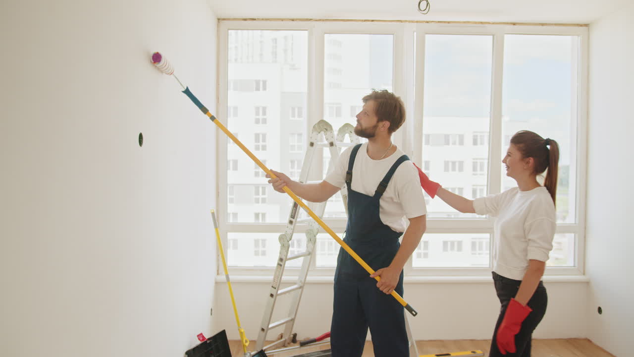 пара рисует стену в своем доме