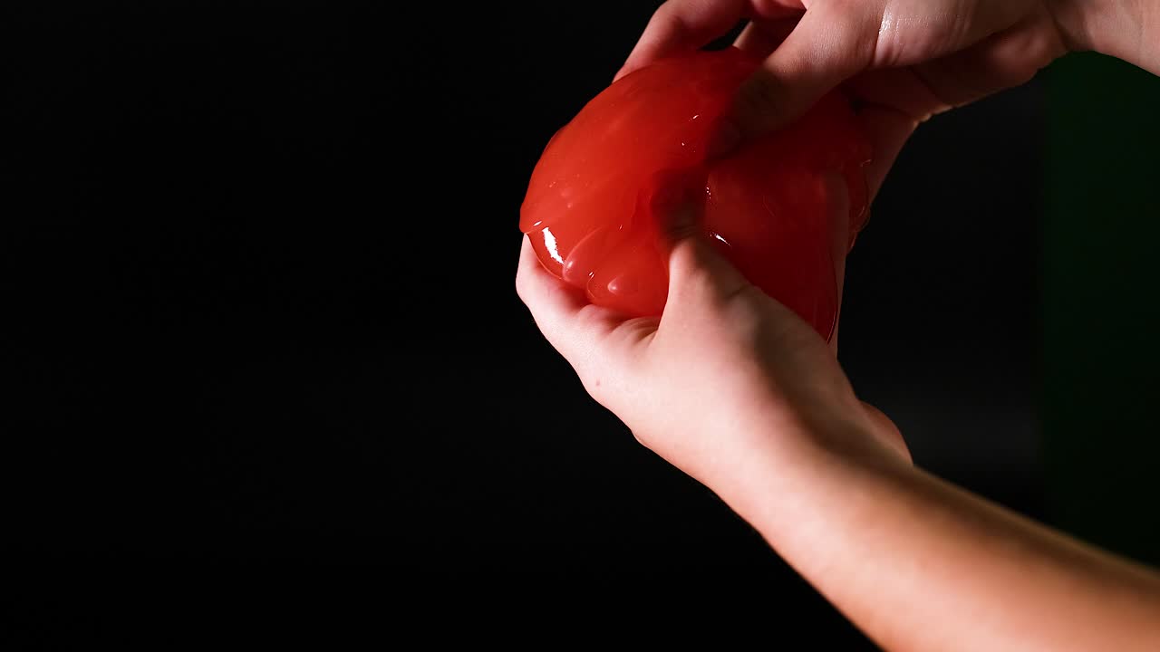 руки, манипулирующие эластичной красной слизью