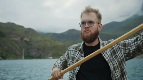 man paddling a boat on a mountain lake