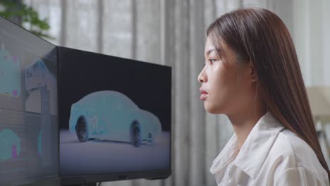 아시아 여성 자동차 디자이너가 머리를 흔들며 스튜디오의 데스크 컴퓨터에서 ev 자동차의 3d 모델을 작업하는 데 피곤합니다.