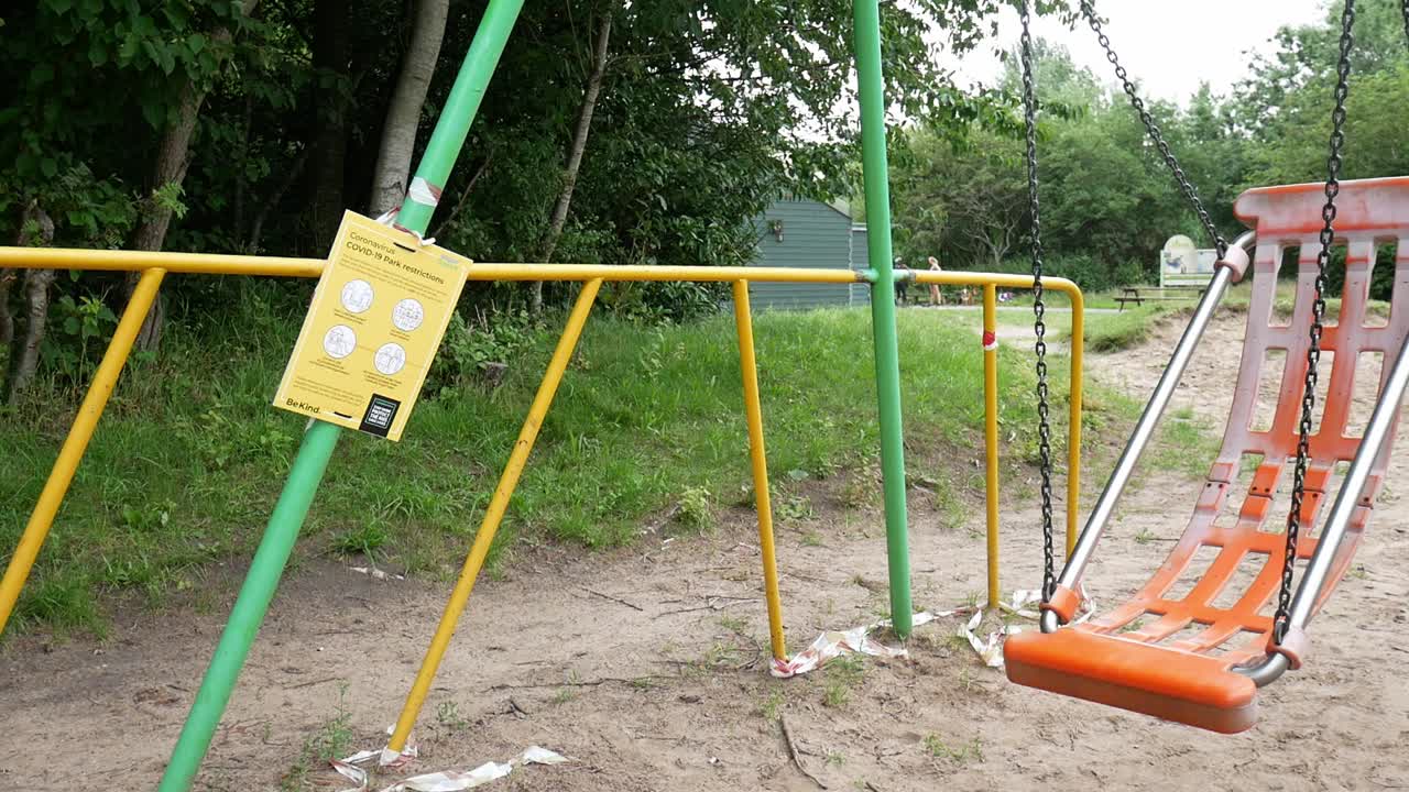 Public warning covid corona virus sign on park playground with empty swing