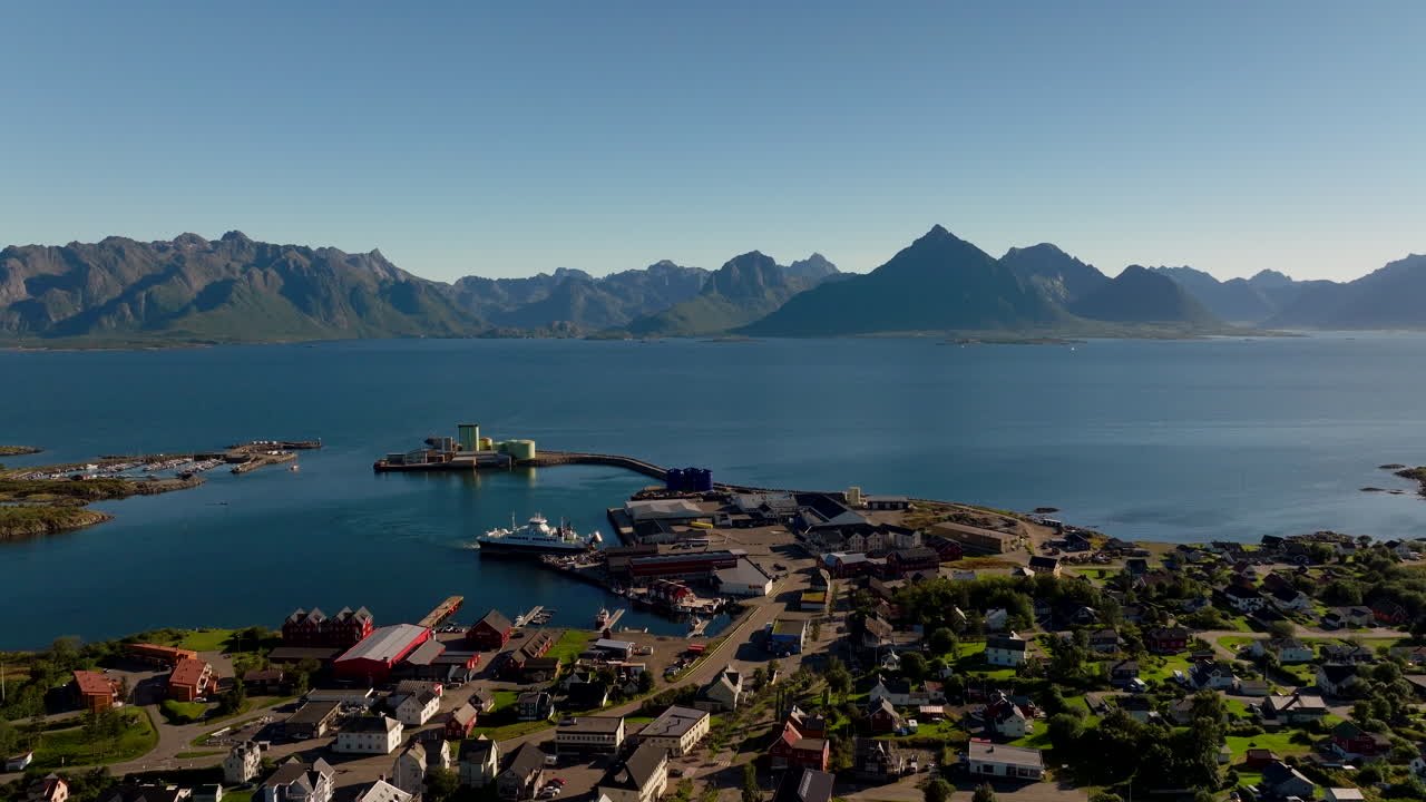 Aerial view, Melbu town in Hadsel Municipality, Lofoten Islands, Norway, during golden hour, revealing the scenic harbour, fishing docks, and fjord coastline beneath mountain peaks