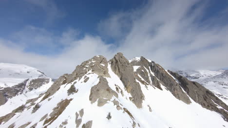 Aerial-forward-over-snowy-rocky-mountain-on-sunny-day,-Pyrenees