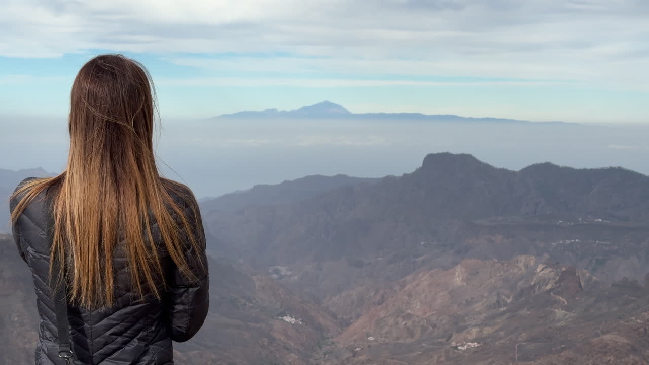 Tourist enjoying the view of Teide volcano from Roque Nublo, Gran Canaria, Canary Islands, Spain