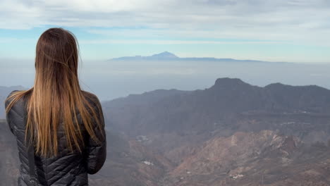 tourist enjoying the view of teide volcano from roque nublo, gran canaria, canary islands, spain