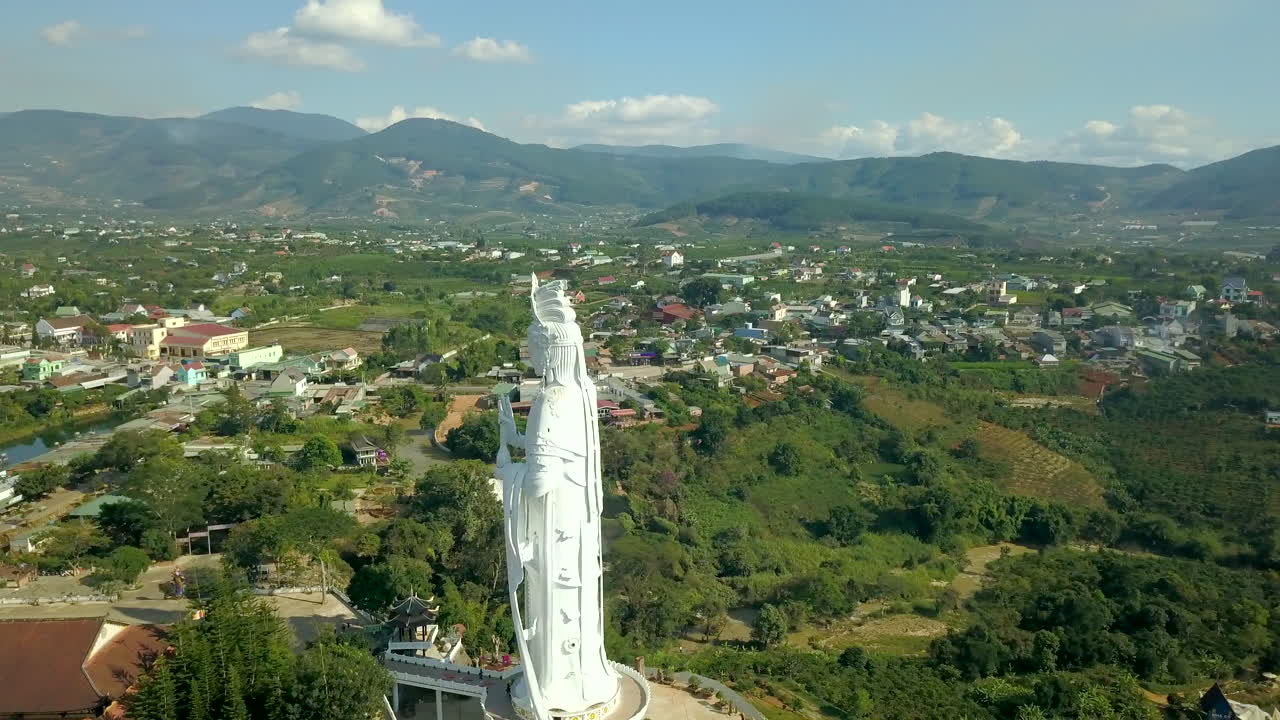 Drone footage of giant religious statue and Elephant waterfall on stones in Vietnam, Dalat. Village and road with pond and trees and nature.