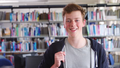 retrato de un estudiante de sexo masculino de pie en la biblioteca de la universidad