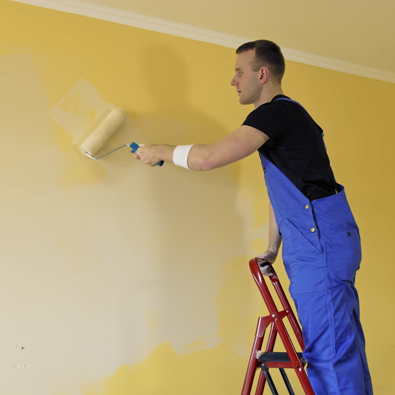 Painting wall with roller brush. Young man painting wall, using roller brush