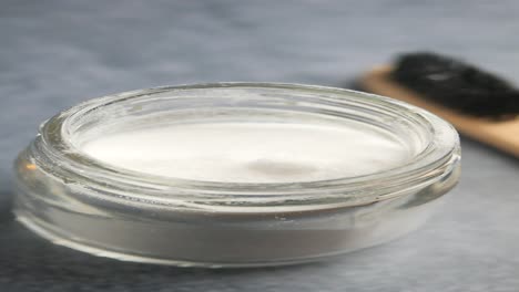 tooth powder in glass jar with wooden toothbrush