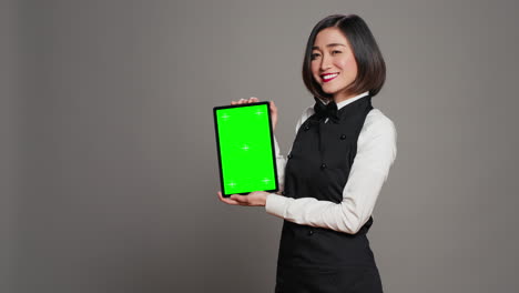 asian restaurant hostess showing greenscreen display in studio