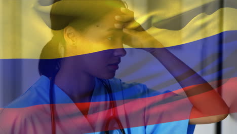 bandera de colombia ondeando contra una trabajadora de salud afroamericana estresada en el hospital