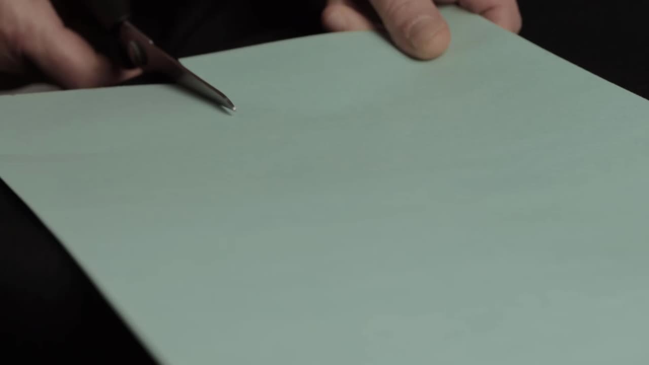 Hands cutting paper card with scissors