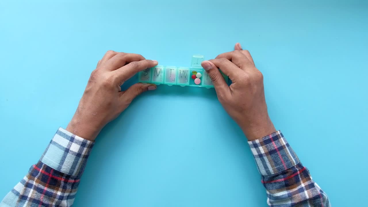 Person using a weekly pill organizer