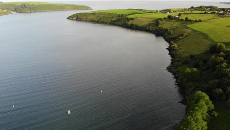 drone footage of green rolling hills and a place where ocean and river meet