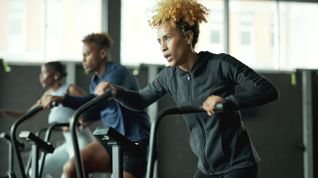 personas haciendo ejercicio en bicicletas de ejercicio en un gimnasio