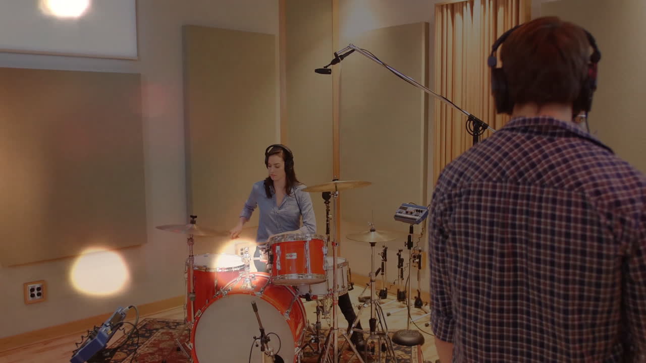 Woman drummer sitting at red drum kit in recording studio, with floating waveform mic icons