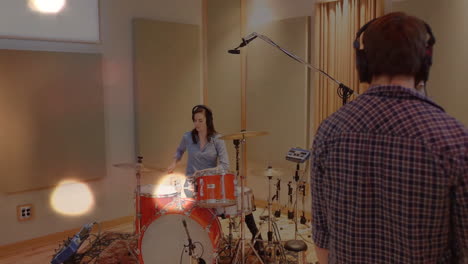 woman drummer sitting at red drum kit in recording studio, with floating waveform mic icons