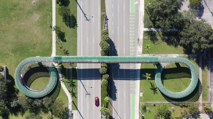 An aerial view directly over a pedestrian walkway which crosses a six lane highway on a sunny day in Florida