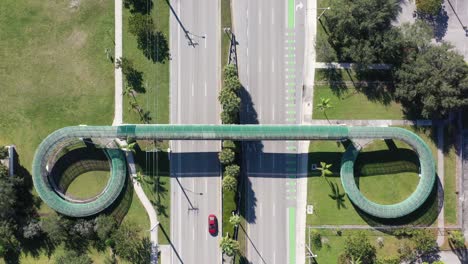 an aerial view directly over a pedestrian walkway which crosses a six lane highway on a sunny day in florida