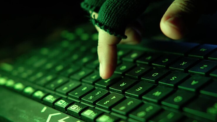 Hacker taster på tastatur i mørkt rum med grønt lys