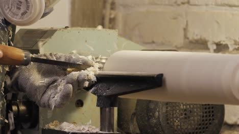 woodworker planing a table leg with wood chips flying