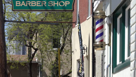 cartel de barbería con poste de barbero y edificios adyacentes