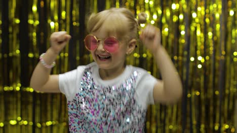 Child-dancing,-show-amazement,-fooling-around,-smiling.-Girl-posing-on-background-with-foil-curtain